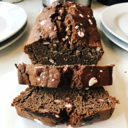 Für unser köstliches Schokoladen-Pfefferminz-Brot brauchen Sie folgende Hauptzutaten: - 2 Tassen Weizenmehl - 1 Tasse Kristallzucker - ½ Tasse ungesüßtes Kakaopulver - 1 Teelöffel Backpulver - ½ Teelöffel Natron - ¼ Teelöffel Salz - 1 Tasse Milch - ⅓ Tasse Pflanzenöl - 2 große Eier - 1 Teelöffel Vanilleextrakt - 1 Teelöffel Pfefferminzextrakt - ½ Tasse semi-süße Schokoladenstückchen - ½ Tasse zerbröselte Pfefferminzbonbons Diese Zutaten arbeiten zusammen, um das Brot saftig und schokoladig zu machen. Das Kakaopulver gibt dem Brot einen reichen Geschmack. Die Pfefferminzbonbons bringen frische, die gut mit der Schokolade harmoniert. Um das Brot noch festlicher zu gestalten, können Sie einige zusätzliche Zutaten für die Dekoration verwenden: - Schokoladensoße - Zerbröselte Pfefferminzbonbons Ein paar Tropfen Schokoladensoße auf den Brotscheiben machen das Brot noch verlockender. Die zusätzlichen Pfefferminzbonbons geben dem Brot eine schöne Optik und zusätzlichen Crunch. Falls Sie einige Zutaten nicht zur Hand haben oder Alternativen benötigen, hier sind einige Vorschläge: - Statt Weizenmehl können Sie auch Mandelmehl verwenden. - Verwenden Sie Kokosmilch anstelle von normaler Milch für eine milchfreie Version. - Für eine vegane Option, ersetzen Sie die Eier durch einen Apfelmus oder Leinsamen. Diese Alternativen helfen Ihnen, das Rezept an Ihre Bedürfnisse anzupassen, ohne den Geschmack zu verlieren. Experimentieren Sie und finden Sie die beste Kombination für sich! {{ingredient_image_2}} Heize den Ofen auf 175°C vor. Fette eine Kastenform (9x5 Zoll) ein. Das hilft dem Brot, nicht zu kleben. In einer großen Schüssel vermische: - 2 Tassen Weizenmehl - 1 Tasse Kristallzucker - ½ Tasse ungesüßtes Kakaopulver - 1 Teelöffel Backpulver - ½ Teelöffel Natron - ¼ Teelöffel Salz Rühre alles gut um. Das sorgt für einen gleichmäßigen Geschmack im Brot. In einer anderen Schüssel kombiniere: - 1 Tasse Milch - ⅓ Tasse Pflanzenöl - 2 große Eier - 1 Teelöffel Vanilleextrakt - 1 Teelöffel Pfefferminzextrakt Vermenge alles gründlich. Achte darauf, dass es gut vermischt ist. Gieße die feuchten Zutaten in die trockenen Zutaten. Rühre nur kurz, bis sich alles verbindet. Ein paar Klümpchen sind okay. Jetzt füge hinzu: - ½ Tasse semi-süße Schokoladenstückchen - ½ Tasse zerbröselte Pfefferminzbonbons Falte sie vorsichtig unter den Teig. Gib den Teig in die Kastenform und glätte die Oberfläche. Backe das Brot 50-60 Minuten. Ein Zahnstocher sollte sauber herauskommen. Lass das Brot etwa 10 Minuten in der Kastenform abkühlen. Danach lege es auf ein Kuchengitter, bis es ganz kalt ist. Ein häufiger Fehler ist, den Teig zu lange zu rühren. Rühren Sie nur bis die Zutaten gemischt sind. Ein paar Klümpchen sind in Ordnung. Übermixen macht das Brot zäh. Achten Sie auch darauf, die Kastenform gut zu fetten. So bleibt das Brot nicht kleben. Vergessen Sie nicht, den Ofen vorzuheizen. Ein kalter Ofen kann das Backergebnis negativ beeinflussen. Die perfekte Konsistenz erreicht man durch das richtige Verhältnis der Zutaten. Messen Sie das Mehl genau ab. Zu viel Mehl macht das Brot trocken. Die Mischung sollte dickflüssig, aber nicht zu fest sein. Wenn Sie die feuchten Zutaten hinzufügen, lassen Sie sie langsam in die trockenen Zutaten fließen. Das sorgt für eine gleichmäßige Verteilung. Um den besten Geschmack zu erzielen, verwenden Sie frische Zutaten. Hochwertige Schokolade und Pfefferminzextrakt machen einen großen Unterschied. Fügen Sie die Schokoladenstückchen und Bonbons am Ende hinzu. So bleiben sie gut sichtbar und sorgen für einen schönen Crunch. Lassen Sie das Brot nach dem Backen etwas abkühlen. So setzen sich die Aromen besser. Pro Tipps Verwenden Sie hochwertige Schokolade: Hochwertige semi-süße Schokoladenstückchen verleihen Ihrem Brot einen intensiveren Geschmack. Pfefferminzbonbons richtig zerbröseln: Für eine gleichmäßige Verteilung zerbröseln Sie die Pfefferminzbonbons am besten in einem Gefrierbeutel mit einem Nudelholz. Ofen vorheizen: Stellen Sie sicher, dass der Ofen vollständig vorgeheizt ist, um ein gleichmäßiges Backen zu gewährleisten. Brotschneiden: Lassen Sie das Brot vollständig abkühlen, bevor Sie es schneiden, damit die Scheiben nicht zerbröckeln. {{image_4}} Für ein glutenfreies Brot wähle einfach glutenfreies Mehl. Du brauchst etwa zwei Tassen der Mischung. Achte darauf, dass die anderen Zutaten glutenfrei sind. Die Textur wird etwas anders sein, bleibt aber lecker. Viele genießen diese Variante genauso wie das Original. Um eine vegane Version zu machen, ersetze die Eier durch Apfelmus oder Leinsamen. Verwende eine pflanzliche Milch wie Mandel- oder Hafermilch. Achte darauf, dass der Vanille- und Pfefferminzextrakt vegan ist. Das Brot bleibt saftig und voller Geschmack. Du wirst den Unterschied kaum merken! Du kannst dein Brot mit weiteren Zutaten aufpeppen. Füge zum Beispiel Nüsse oder getrocknete Früchte hinzu. Walnüsse oder Mandeln passen gut. Du kannst auch andere Schokoladensorten verwenden, wie weiße oder dunkle Schokolade. Für extra Frische probiere Orange- oder Zitronenschale. Die Aromen machen das Brot noch spannender und interessanter. Um das Schokoladen-Pfefferminz-Brot frisch zu halten, verpacke es gut. Du kannst es in Frischhaltefolie einwickeln. Eine luftdichte Box ist auch eine gute Wahl. So bleibt das Brot saftig und lecker. Vermeide es, das Brot in den Kühlschrank zu legen. Kälte kann die Textur beeinträchtigen. Im Kühlschrank hält das Brot etwa 3 bis 4 Tage. Wenn du es länger aufbewahren möchtest, friere es ein. Das Brot bleibt im Gefrierschrank bis zu 3 Monate frisch. Achte darauf, es gut einzupacken, damit es keine Frostschäden erleidet. Um das Brot wieder warm zu machen, kannst du den Ofen nutzen. Heize ihn auf 150°C vor. Lege das Brot auf ein Backblech und backe es für etwa 10 Minuten. So bleibt es schön weich. Du kannst auch eine Mikrowelle verwenden. Erwärme eine Scheibe für etwa 15-20 Sekunden. Achte darauf, dass es nicht zu heiß wird. Das Brot braucht 50 bis 60 Minuten im Ofen. Ich empfehle, nach 50 Minuten zu prüfen. Stecken Sie einen Zahnstocher in die Mitte des Brotes. Wenn er sauber herauskommt, ist das Brot fertig. Wenn nicht, backen Sie es noch einige Minuten länger. Ja, Sie können die Pfefferminzbonbons weglassen. Das Brot schmeckt auch ohne sie gut. Es bleibt schokoladig und lecker. Wenn Sie eine andere Note möchten, fügen Sie Nüsse oder andere Schokoladenstückchen hinzu. Zu diesem Brot passen viele Beilagen. Ein Klecks Schlagsahne macht es besonders. Auch eine warme Schokoladensoße ist köstlich. Für einen frischen Geschmack können Sie frische Beeren servieren. Zusammenfassend haben wir heute die Zutaten und die Schritte für das Schokoladen-Pfefferminz-Brot besprochen. Ich habe Tipps gegeben, um häufige Fehler zu vermeiden und die besten Variationen zu entdecken. Achte auf die Aufbewahrung, damit dein Brot frisch bleibt. Das Experimentieren mit Aromen und Varianten macht das Backen spannend. Du bist nun bereit, dein eigenes Brot zu backen und deine Gäste zu beeindrucken. Viel Spaß beim Backen!