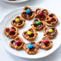 - Mini-Brezeln - Schokoladen-Hugs - M&M's - Backpapier Für die Zubereitung der Pretzel Hugs benötigen Sie nur vier einfache Zutaten. Diese Snacks sind schnell gemacht und schmecken köstlich. Die Mini-Brezeln sind das Herzstück. Sie sind knusprig und salzig, was perfekt mit der Schokolade harmoniert. Die Schokoladen-Hugs sind eine Mischung aus weißer und Milchschokolade. Diese süßen Hugs schmelzen leicht und sorgen für eine cremige Füllung. Wählen Sie Ihre Lieblingsfarben für die M&M's. Sie bringen Farbe und einen fruchtigen Crunch in die Brezeln. Schließlich brauchen Sie Backpapier. Es verhindert, dass die Brezeln am Blech festkleben. Mit diesen Zutaten sind Sie bereit, leckere Pretzel Hugs zu zaubern! {{ingredient_image_2}} Heize deinen Ofen auf 175°C (350°F) vor. Lege ein Backblech mit Backpapier aus. Das Backpapier hilft, die Brezeln nicht zu kleben. Nimm die Mini-Brezeln und lege sie in einer Schicht auf das Backblech. Achte darauf, dass sie sich nicht berühren. So backen sie gleichmäßig. Öffne die Tüte mit den Schokoladen-Hugs. Lege einen Hug auf jede Brezel. Dies sorgt für eine köstliche süße Note. Backe die Brezeln im Ofen für etwa 3-5 Minuten. Die Hugs sollen weich sein, aber nicht komplett schmelzen. Überprüfe sie regelmäßig, damit sie nicht verbrennen. Nimm das Blech aus dem Ofen. Drücke sofort ein M&M in die Mitte jedes geschmolzenen Hugs. Lass die Pretzel Hugs bei Raumtemperatur abkühlen. Für einen schnelleren Prozess kannst du sie auch für 10-15 Minuten in den Kühlschrank stellen. Nach dem Abkühlen sind sie bereit zum Genießen! Die ideale Backtemperatur für Pretzel Hugs ist 175°C. Diese Temperatur sorgt dafür, dass die Hugs weich werden, ohne zu schmelzen. Backen Sie die Brezeln 3 bis 5 Minuten. Achten Sie darauf, die Brezeln genau im Auge zu behalten, um ein Überbacken zu vermeiden. Um den Abkühlprozess zu beschleunigen, können Sie die Pretzel Hugs in den Kühlschrank stellen. Legen Sie sie für 10 bis 15 Minuten hinein. So werden sie schnell fest und sind bald bereit zum Genießen. Für eine schöne Präsentation können Sie die Pretzel Hugs auf einer großen Platte anrichten. Verwenden Sie bunte M&M's, um einen lebhaften Effekt zu erzielen. Eine hübsche Schleife um die Platte macht sie zu einem tollen Geschenk. Pro Tipps Die richtige Brezel: Verwenden Sie Mini-Brezeln, um die perfekte Größe zu erzielen, die gut mit den Hugs harmoniert. Die Backzeit überwachen: Behalten Sie die Brezeln während des Backens im Auge, um sicherzustellen, dass die Hugs weich sind, aber nicht schmelzen. Kühlen für beste Ergebnisse: Stellen Sie die Brezeln nach dem Backen in den Kühlschrank, um die Hugs schnell zu festigen und die Textur zu verbessern. Farbige M&M's: Wählen Sie M&M's in verschiedenen Farben, um einen fröhlichen und ansprechenden Snack zu kreieren. {{image_4}} Für die Pretzel Hugs können Sie verschiedene Schokoladensorten verwenden. Statt der Schokoladen-Hugs können Sie auch Zartbitterschokolade nehmen. Diese Option gibt den Hugs einen intensiveren Geschmack. Weißer Schokolade ist ebenfalls eine tolle Wahl. Sie sorgt für eine süße, cremige Note. M&M's sind nicht die einzige Option. Sie können auch andere Süßigkeiten verwenden. Probieren Sie bunte Smarties oder kleine Schokoladenstückchen. Diese bringen neue Aromen und Farben ins Spiel. Zusätzlich zu M&M's können Sie Ihre Pretzel Hugs dekorieren. Streuen Sie bunte Streusel über die geschmolzenen Hugs. Das macht sie noch ansprechender. Nüsse oder Karamellstückchen sind auch eine tolle Ergänzung. Diese Toppings geben den Hugs einen knackigen Biss. Für einen besonderen Twist können Sie etwas Meersalz hinzufügen. Das Salz ergänzt die Süße der Schokolade perfekt. Wenn Sie nach diätfreundlichen Optionen suchen, gibt es viele Möglichkeiten. Verwenden Sie glutenfreie Brezeln, um eine glutenfreie Version zu machen. Diese sind leicht im Handel erhältlich. Zuckerfreie Schokolade ist eine weitere gute Wahl. Sie bietet den süßen Geschmack ohne den Zucker. So können Sie den Snack genießen, ohne sich schuldig zu fühlen. Um Pretzel Hugs richtig zu lagern, benötigst du einen luftdichten Behälter. Achte darauf, dass der Behälter sauber und trocken ist. Platziere die Hugs in einer einzigen Schicht. So bleibt die Form erhalten, und sie kleben nicht zusammen. Du kannst sie auch zwischen Lagen von Backpapier aufbewahren. Das hilft, die Brezeln frisch zu halten. Lagere die Pretzel Hugs an einem kühlen, trockenen Ort, fern von direkter Sonneneinstrahlung. Pretzel Hugs sind am besten, wenn du sie frisch genießt. Sie halten sich jedoch bis zu einer Woche, wenn du sie richtig lagerst. Um die Frische zu verlängern, kannst du sie im Kühlschrank aufbewahren. So bleiben sie länger knackig. Achte darauf, den Behälter gut zu verschließen. Wenn du merkst, dass sie weich werden, kannst du sie kurz im Ofen aufbacken. So bekommst du die Knusprigkeit zurück. Pretzel Hugs sind am besten frisch. Sie halten sich in einem luftdichten Behälter. Lagern Sie sie bei Raumtemperatur. So bleiben sie knackig. Wenn Sie die Brezeln kühlen, können sie länger frisch bleiben. In der Regel bleiben sie bis zu einer Woche gut. Achten Sie darauf, sie vor Feuchtigkeit zu schützen. Ja, Sie können andere Schokoladensorten verwenden. Probieren Sie Zartbitterschokolade oder Vollmilchschokolade. Weiße Schokolade schmeckt auch gut. Für Abwechslung können Sie sogar aromatisierte Schokoladen ausprobieren. Kombinieren Sie verschiedene Sorten für interessante Geschmäcker. Ihre Kreativität ist hier gefragt! Pretzel Hugs sind nicht glutenfrei, da Mini-Brezeln in der Regel Gluten enthalten. Wenn Sie glutenfreie Snacks möchten, suchen Sie nach glutenfreien Brezeln. Viele Marken bieten leckere Optionen an. So können Sie trotzdem genießen, ohne auf den Geschmack zu verzichten. Achten Sie stets auf das Etikett! In diesem Artikel haben wir die Zutaten und Schritte für die einfachen Pretzel Hugs durchgegangen. Wir haben erfahren, wie man die Brezeln richtig anrichtet, perfekt backt und schön präsentiert. Du kannst mit verschiedenen Schokoladensorten experimentieren und auch diätfreundliche Varianten ausprobieren. Diese Snacks sind einfach und lecker. Sie eignen sich wunderbar für Feiern oder als Geschenk. Mit meinen Tipps wird dein Ergebnis garantiert toll. Viel Spaß beim Ausprobieren!